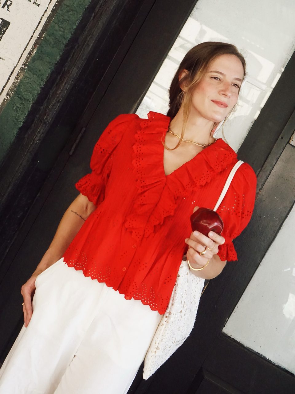 Ultra Pink red blouse, smiling, apple in hand.